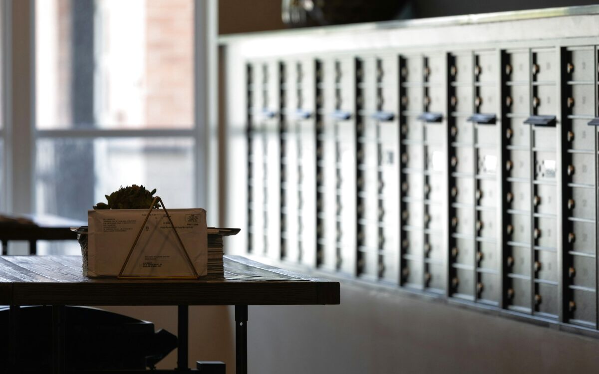 A wall of private mailboxes beside a table with incoming mail